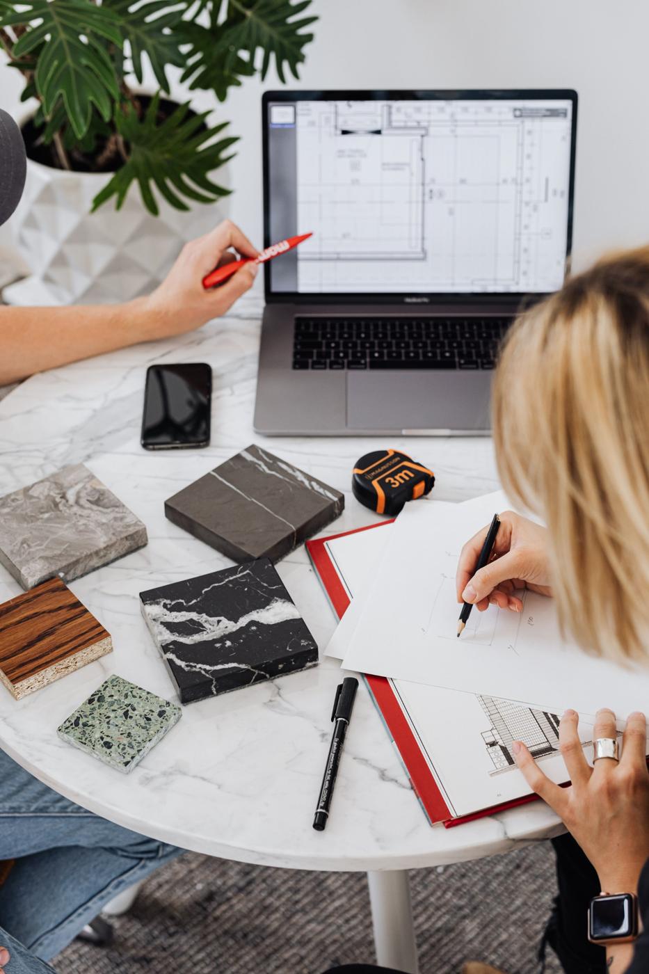 Designer sketching plans beside stone and wood finish samples