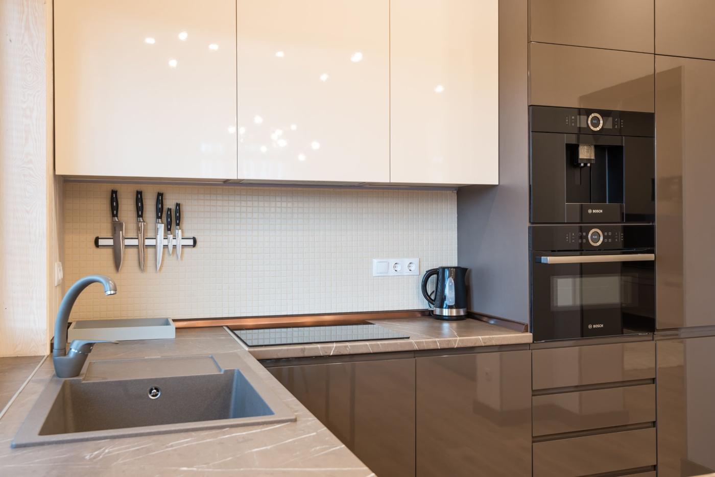 Modern kitchen with glossy cream upper cabinets and built-in ovens