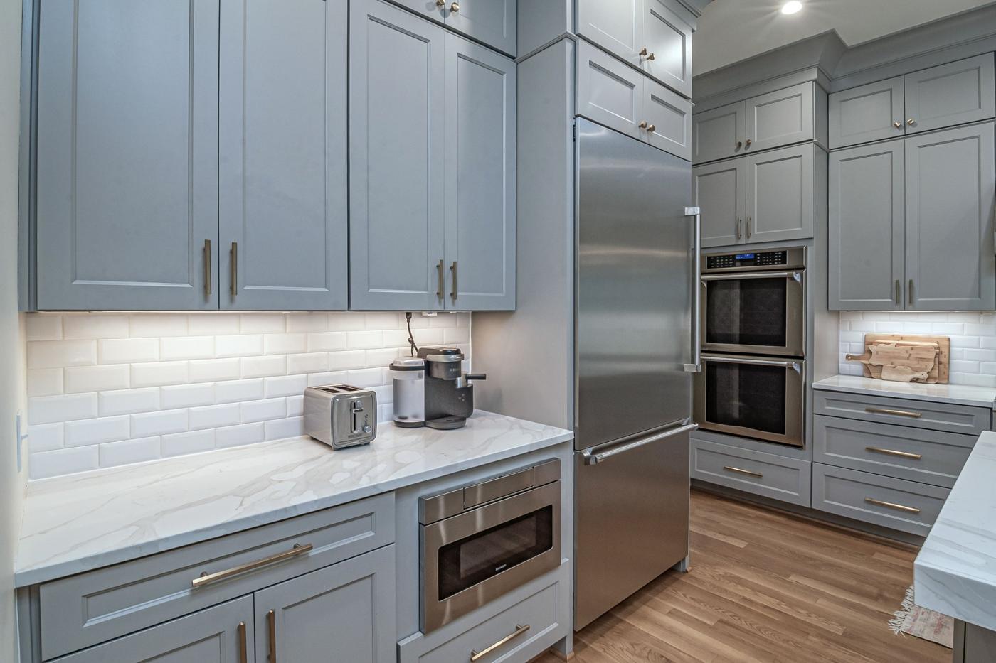 Kitchen with gray shaker cabinets, quartz counters, and double wall ovens